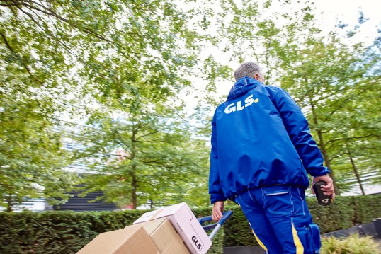 GLS Zustellfahrer stellt ein Paket beim Kunden zu