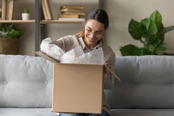 e-balik, sender on a couch packing a parcel to be sent