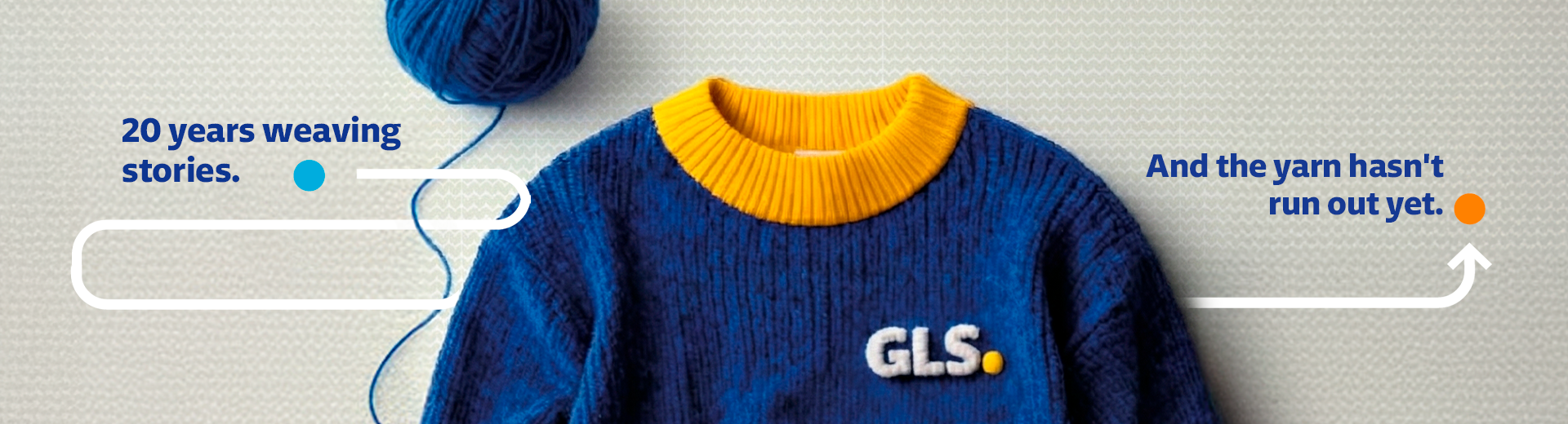 Blue knitted sweater with a yellow collar and GLS logo, accompanied by a ball of yarn and a corporate message celebrating 20 years of storytelling and brand heritage