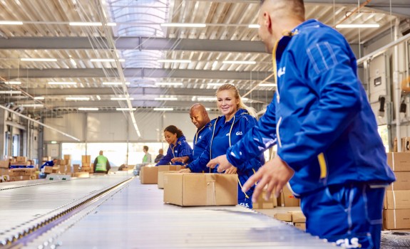 GLS employees working together by the parcel conveyor belt.