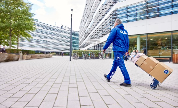 GLS employee delivering parcels on the street with trolley.