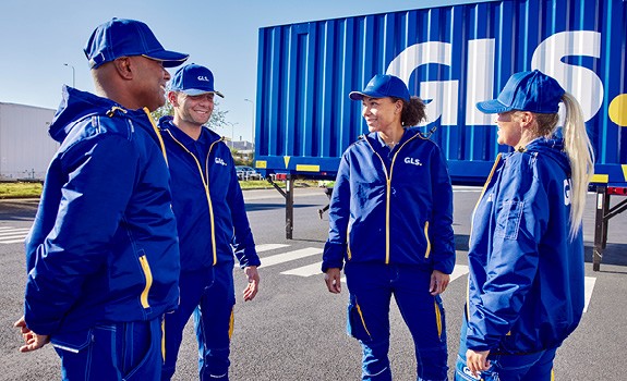 Employés GLS en tenue professionnelle sur site logistique, devant un conteneur de transport, illustrant les services de livraison de colis et la logistique du dernier kilomètre.