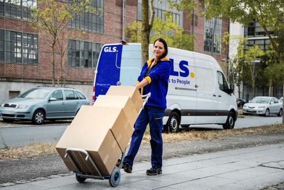delivery woman moving parcels in front of a GLS van