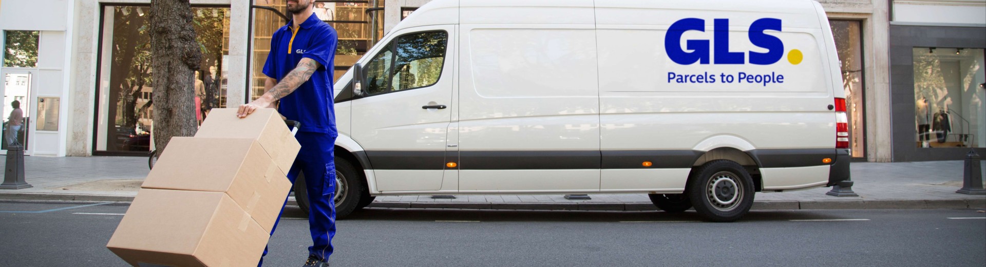 Delivery man carries parcels in front of his van